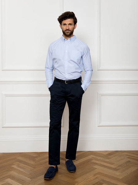 Man wearing long sleeved shirt with sky blue and white thin stripe and the inside collar and cuffs trimmed with gingham pattern. Made with 100% cotton in Thomas Mason fabric.